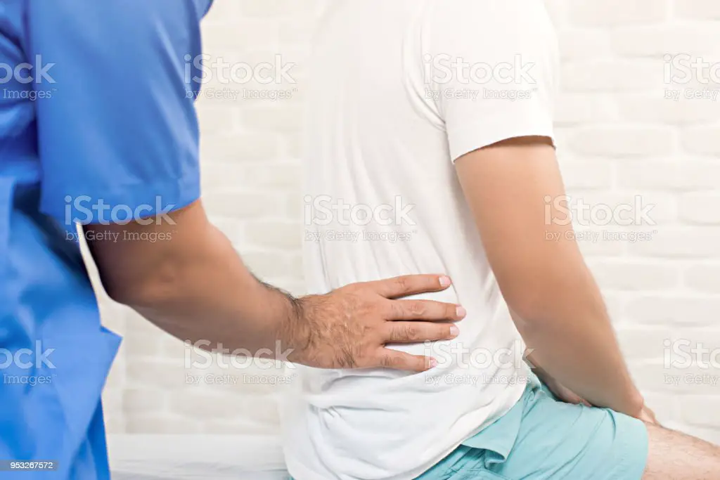 Male Doctor Therapist Treating Lower Back Pain Patient In Clinic Stock ...